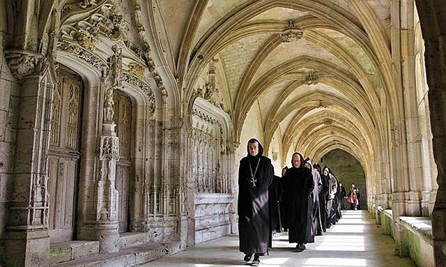 Monges no claustro da Abadia de Saint-Wandrille de Fontenelle , que integra o Circuito das Abadias da Normandia,na França - reprodução