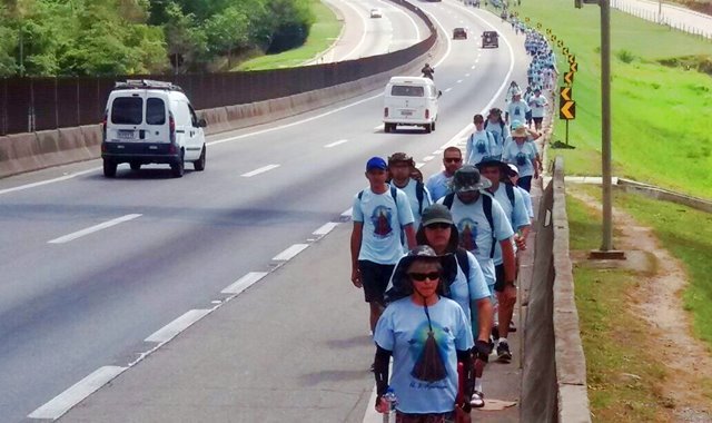 Grupo de romeiros caminhando no acostamento da Via Dutra rumo a Aparecida
